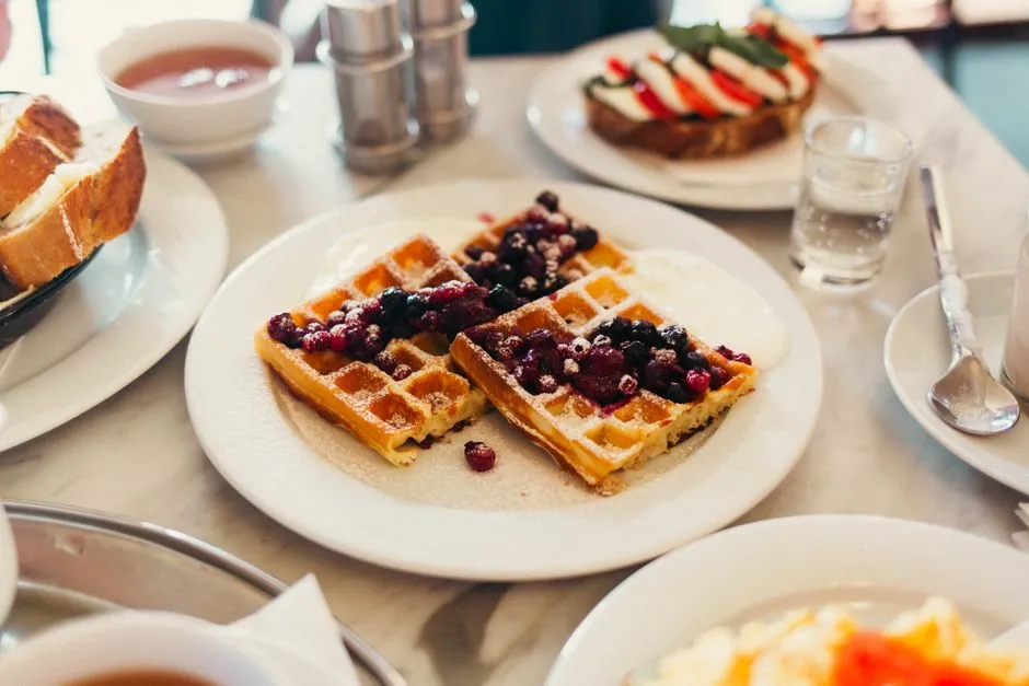 Plate of waffles topped with berries and cream at a breakfast table